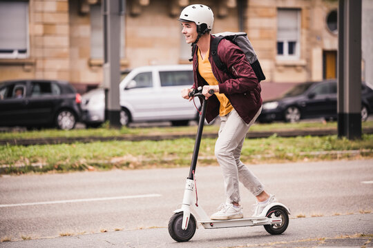 Smiling young man riding scooter in the city