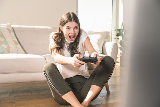 Happy young woman playing video game at home