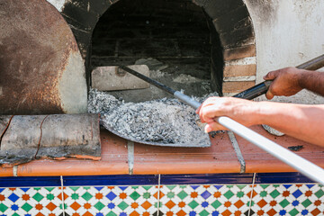 Chefs collecting ash from wood burning stove with shovels