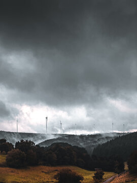 dramatische Landschaftsaufnahme eines Windparks mit bedecktem Himmel und Nebel