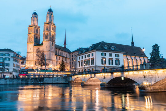 Switzerland, Zurich, Grossmunster church and Munsterbrucke over Limmat river at dusk