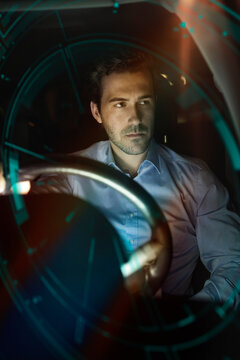 Businessman in car at night surrounded by virtual tachometer