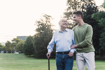 Young man assisting his grandfather walking in a park