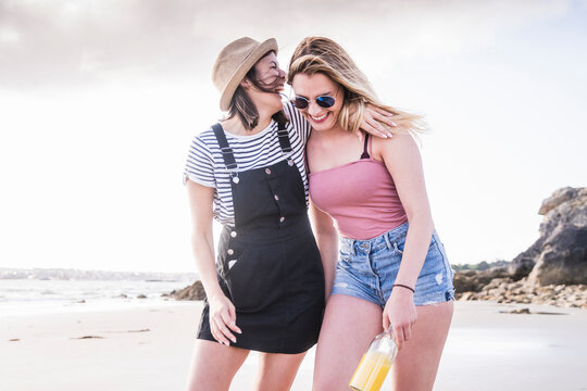 Two girlfriends having fun, walking on the beach