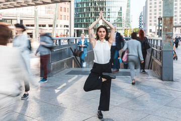 Young businesswoman practising yoga in the city at rush hour, Berlin, Germany
