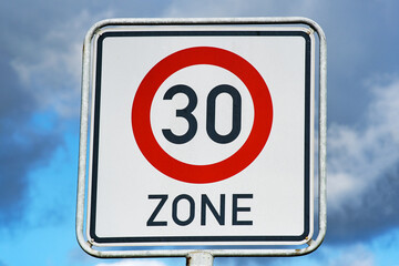Tempolimit Zone 30 Schild vor blauen und leicht bewölktem Himmel
