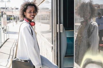 Portrait of a smiling young woman entering a train