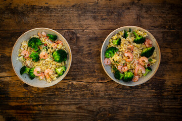 Two bowls of fried rice with shrimps, broccoli, chili peppers, cilantro and ginger