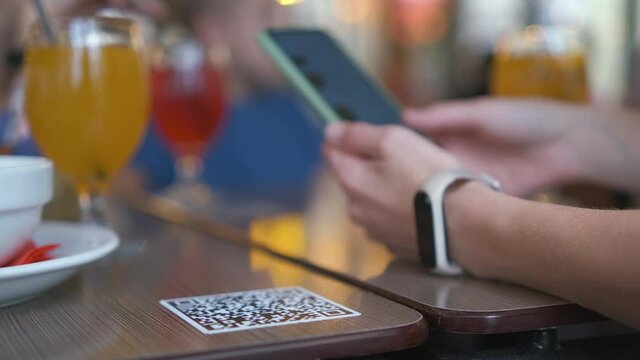Closeup of guest hand ordering meal in restaurant while scanning qr code with mobile phone for online menu.