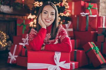 Obraz na płótnie Canvas Photo of pretty cute young lady wear red pullover smiling holding christmas present arm cheekbone indoors house home room