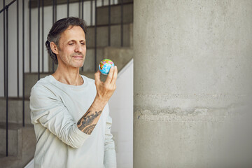 Senior man holding mini globe in a loft flat