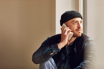 Man refurbishing shop location, sitting on windowsill, talking on the phone