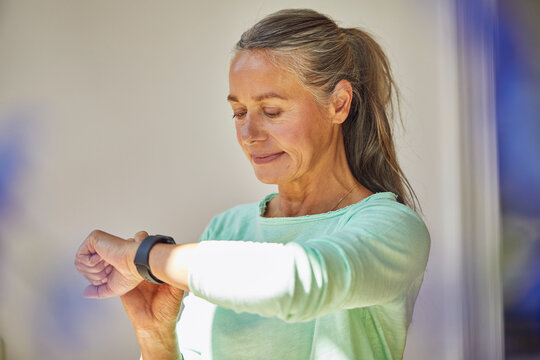 Confident Woman Checking The Time Against Wall At Home