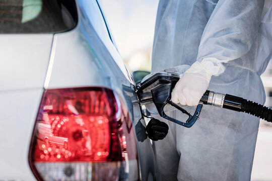 Close-up of man wearing protective clothing refueling car at gas station