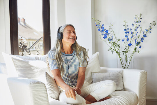Happy woman listening to music through headphones on sofa at home