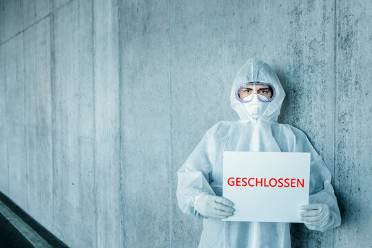 Portrait of man wearing protective clothing holding a sign