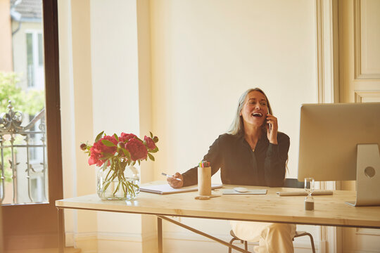 Mature businesswoman talking on phone while working at home