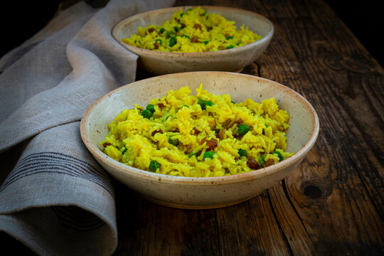 Bowls of pilau rice with green peas, turmeric and raisins