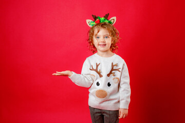 little girl in deer horns on a red background, christmas, new year