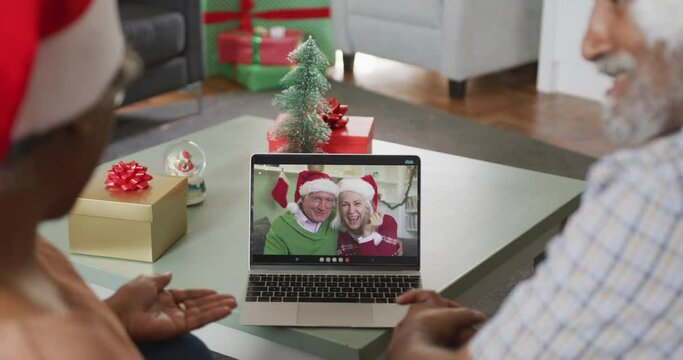 Happy african american senior couple on video call with senior friends at christmas