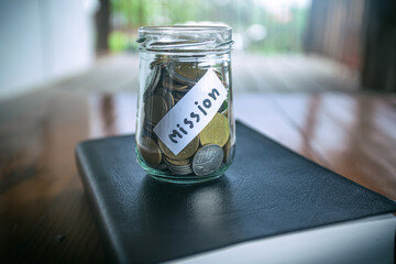 Savings jars full of money for mission with Bible, christian concept.
