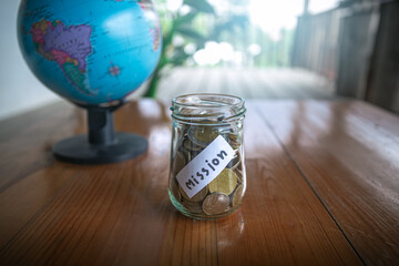 Savings jars full of money for mission on wooden desk, christian concept.