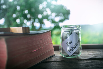 Savings jars full of money for mission with Bible. - obrazy, fototapety, plakaty