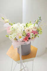 Floral bunch in round grey box. Fresh delicate bouquet of beautiful mixed flowers in light room. The work of a professional florist. 