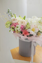 Floral bunch in round grey box. Fresh delicate bouquet of beautiful mixed flowers in light room. The work of a professional florist. 