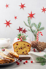 Obraz na płótnie Canvas Festive christmas fruit cake with raisins, cranberries and almonds, decorated with fresh cranberries and rosemary on white table and background. Vertial image.