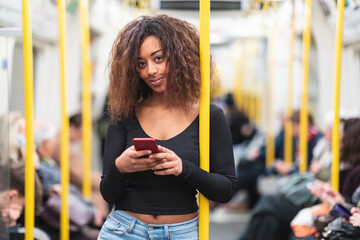 Portrait of smiling young woman with smartphone on a subway