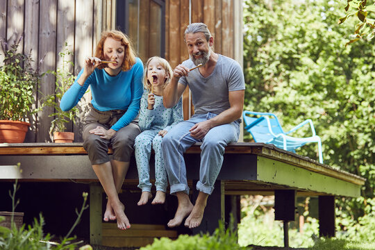 Parents with daughter brushing teeth while sitting outside tiny house
