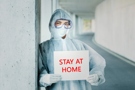 Portrait of man wearing protective clothing holding a 'stay at home' sign