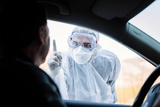 Man wearing protective clothing reprimanding senior man in car