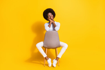 Fototapeta na wymiar Full size photo of optimistic short hair lady hands face look empty space wear white pullover trousers sneakers isolated on yellow background