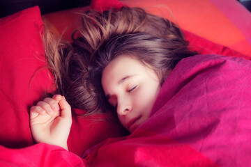 Portrait of girl sleeping in colourful bedding