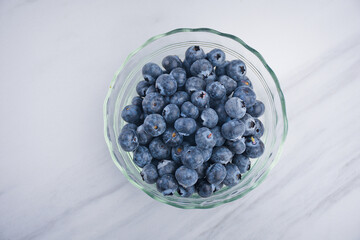 Blueberry fruit in glass cup on white table background