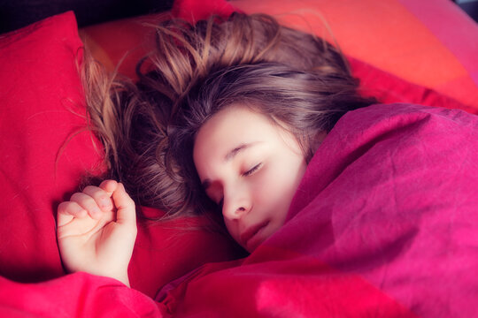Portrait of girl sleeping in colourful bedding