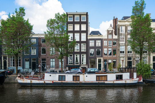 Netherlands, Amsterdam, Barge moored along edge of city canal with row of houses in background