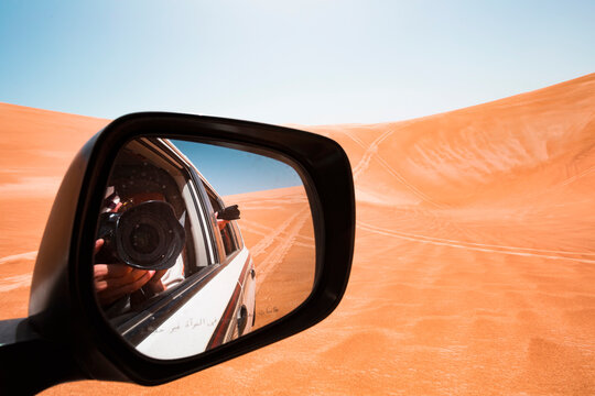 Mirror image of a man taking pictures from a off-road vehicle, Oman, Wahiba Sands