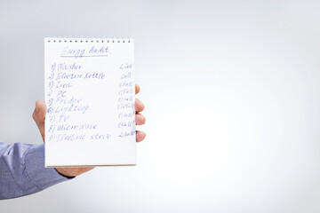 Obraz premium Hand holding notebook with Energy Audit on grey background with copy space.