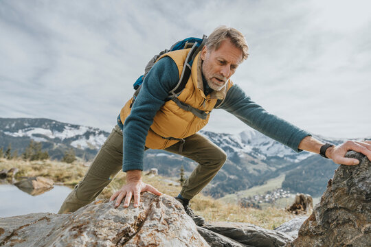 Male tourist climbing on rock against sky at Salzburger Land, Austria
