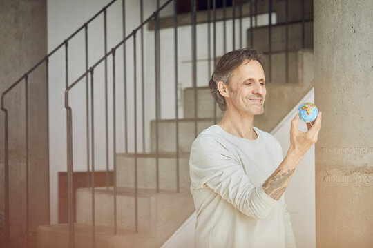 Senior man holding mini globe in a loft flat