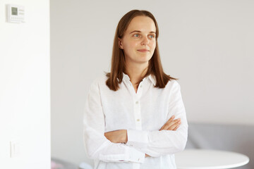 Portrait of attractive young adult woman with dark hair wearing white casual style shirt, standing...