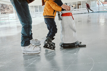 Grandfather and grandson on the ice rink, ice skating, using ice bear figure as prop