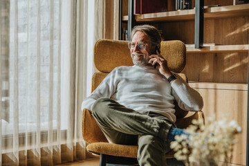 Smiling mature man talking on mobile phone by window