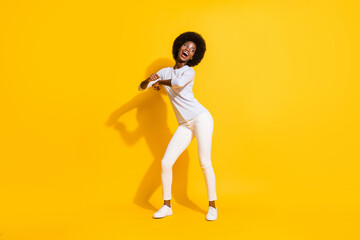 Fototapeta na wymiar Full length portrait of carefree attractive dark skin girl dancing look empty space isolated on yellow color background