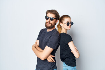 a young couple in black t-shirt sunglasses posing light background