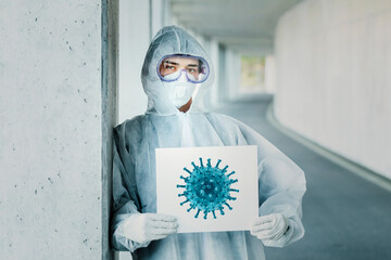 Portrait of man wearing protective clothing holding sign with a depiction of a virus