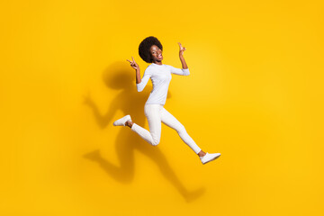 Fototapeta na wymiar Full size profile side photo of dark skin girl run jump up show v-sign isolated on shine yellow color background